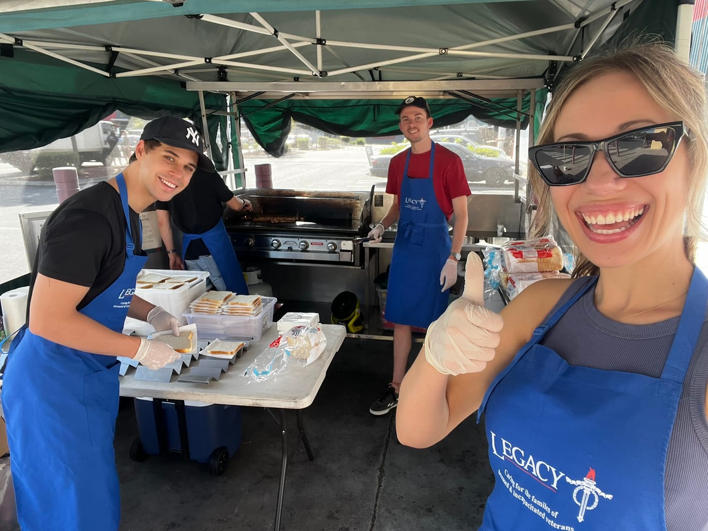 The founders cooking and serving at a Bunnings sausage sizzle in blue Legacy aprons