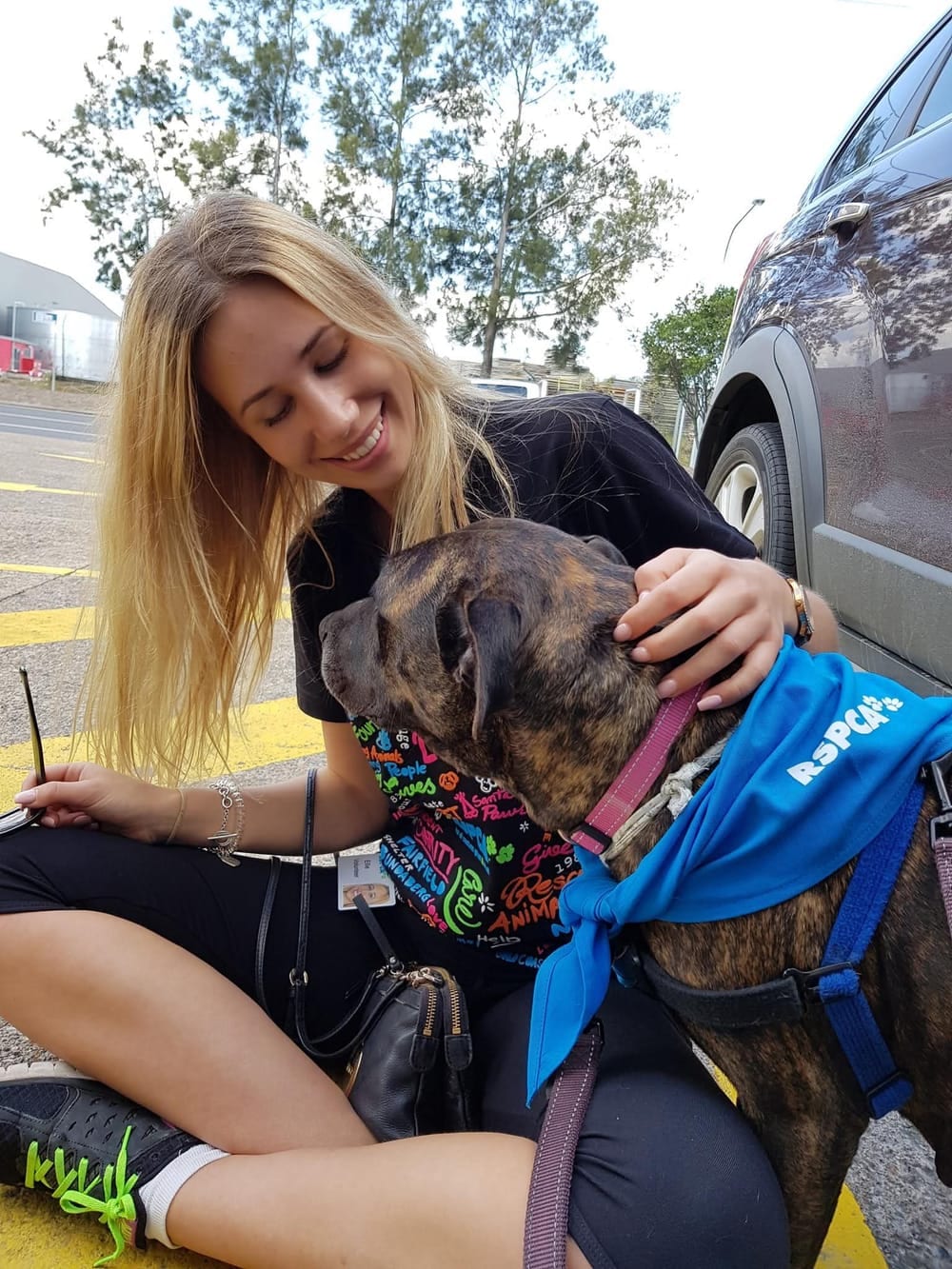 One of the founders volunteering at the RSPCA, cuddling a rescue dog wearing an RSPCA bandana